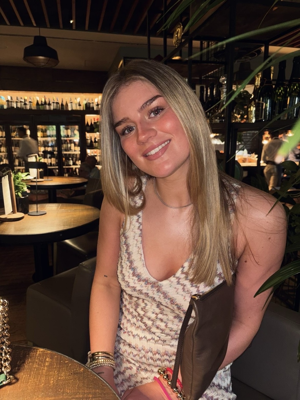 Rachel smiling at a restaurant table in a textured dress